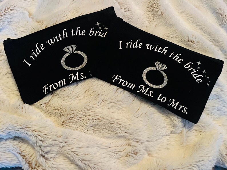 May include: Two black zippered pouches with white text and a diamond ring graphic. One reads "I ride with the brid From Ms." and the other reads "I ride with the bride From Ms. to Mrs."