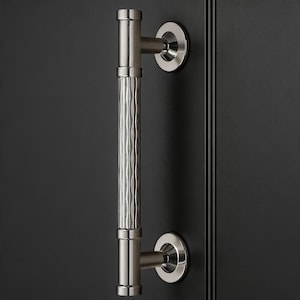 May include: A brushed nickel door pull with a textured, wavy center section. The handle is mounted on a dark surface, showcasing its modern design. The pull is approximately 30 cm in length.