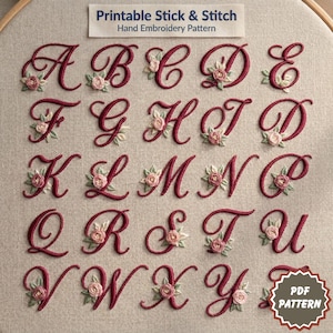 Może przedstawiać: Tamborek do haftu przedstawia alfabet, każda litera w bordowej czcionce skryptowej, ozdobiona małymi akcentami kwiatowymi. Tekst "Printable Stick & Stitch Hand Embroidery Pattern" znajduje się na górze, z grafiką "PDF PATTERN" na dole.