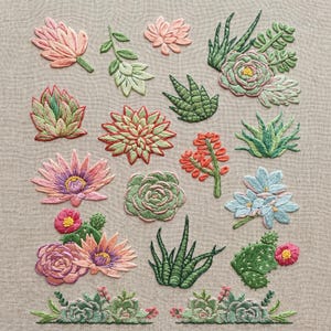 May include: A collection of embroidered succulent and floral motifs on a light beige fabric background. The designs feature various cacti, rosettes, and blooming flowers in shades of pink, green, orange, blue, and purple, arranged in a grid.