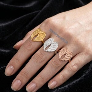 May include: Three rings featuring angel wing designs in gold, silver, and rose gold tones. Each ring displays detailed feather textures on the wings. The text jewelrycraftHA is visible in blue lettering across the center of the image.
