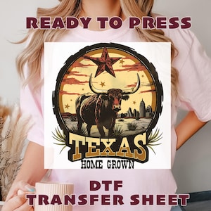 May include: A pink t-shirt featuring a DTF transfer sheet design. The design includes a brown longhorn, a red star, and the words "Texas Home Grown." The words "Ready to Press" and "DTF Transfer Sheet" are also visible.