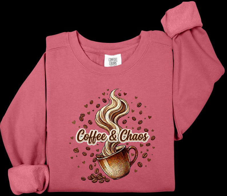 May include: A dusty rose long-sleeve sweatshirt featuring a graphic of a brown coffee mug with swirling steam, surrounded by scattered coffee beans and small hearts. The text Coffee & Chaos is printed in a brown script font across the center.