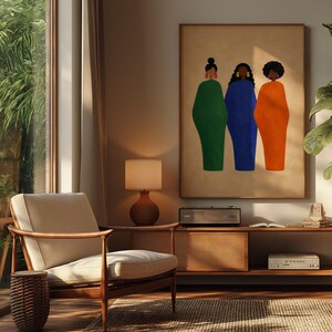 May include: An interior shot features a framed art print with three figures in green, blue, and orange dresses. The artwork hangs above a mid-century modern console with a record player. A beige armchair and a woven side table sit on a textured rug.