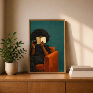 May include: A framed wall art print depicting a person with dark curly hair sitting in an orange armchair, holding an open book in front of their face and a glass of red wine in their other hand, set against a solid dark teal background.
