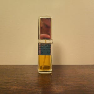 May include: A rectangular glass perfume bottle containing amber-colored liquid. The silver label reads GIVENCHY GENTLEMAN eau de toilette 30 g 20 ml. The bottle features a metallic silver cap and a clear spray tube visible inside the glass container.