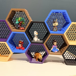 May include: A multi-colored honeycomb-shaped shelf unit with a black mesh backing. The shelves are in various colors, including purple, blue, yellow, and black, and hold small figurines. The figurines include a tree, a rabbit, and characters from popular animated shows.