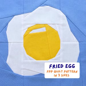 May include: A fabric quilt block featuring a fried egg design. The egg yolk is yellow, surrounded by a white egg white, set against a light blue background. Text on the image reads "FRIED EGG FPP QUILT PATTERN IN 3 SIZES."
