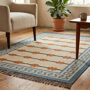 May include: A rectangular rug with a cream backdrop, adorned with brown starburst patterns and black lines. It has a blue border with a Greek key design and fringing. The rug is suitable for a living room.