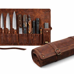 Peut inclure: Une trousse à outils en cuir marron avec plusieurs poches intérieures contenant divers couteaux en métal, un outil multifonction, une lampe de poche et une pierre à aiguiser. La trousse est présentée ouverte et fermée par deux boucles.