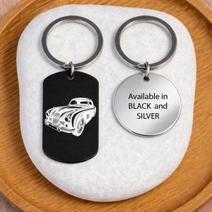 May include: Two keychains with silver rings. One is black and rectangular with a white car illustration. The other is silver and round, with the text "Available in BLACK and SILVER".