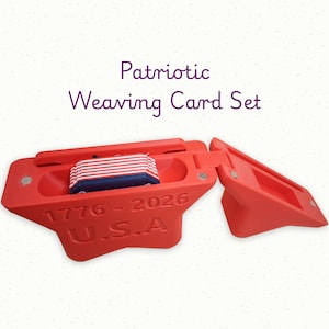 May include: A red plastic weaving card storage case with a hinged lid, containing a stack of small rectangular cards with red, white, and blue stripes. The case features the embossed text 1776 - 2026 and U.S.A. on the front exterior surface.