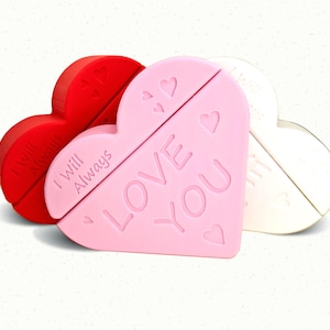 May include: Three heart-shaped trinket boxes in red, pink, and white. The pink heart has the words "LOVE YOU" and small heart designs. The red heart says "I Will Always". The white heart is plain.