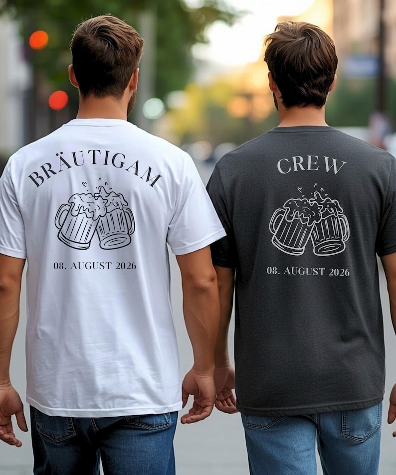 K&ouml;nnte beinhalten: Ein wei&szlig;es T-Shirt mit dem Text BR&Auml;UTIGAM und einer dunklen Grafik von zwei ansto&szlig;enden Bierkr&uuml;gen &uuml;ber dem Datum 08. AUGUST 2026, sowie ein dunkelgraues T-Shirt mit dem Text CREW und einer wei&szlig;en Grafik von zwei Bierkr&uuml;gen &uuml;ber 08. AUGUST 2026.