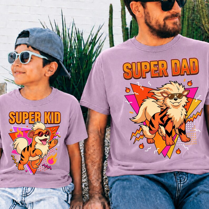 Peut inclure: Deux t-shirts lilas assortis avec les inscriptions "SUPER DAD" et "SUPER KID" en orange. Chaque t-shirt pr&eacute;sente un personnage de dessin anim&eacute; avec des lunettes de soleil et un motif de tigre. Un ensemble amusant pour p&egrave;re et enfant.