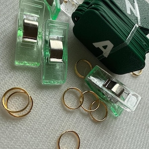 May include: A white ceramic mug with a black handle and the text "But First, Coffee" in a black, handwritten-style font. The mug is on a white surface.