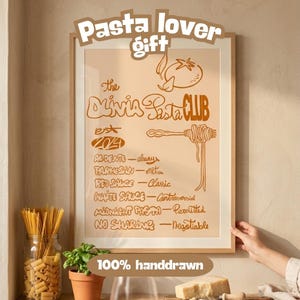 Puede incluir: Un póster enmarcado con el texto "Pasta lover gift" y "The Olivia Pasta Club" en letras marrones. El póster incluye una ilustración de tomate y una lista de términos relacionados con la pasta. Las palabras "100% handdrawn" están en la parte inferior.