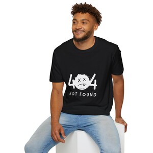 Könnte beinhalten: Schwarzes T-Shirt mit einem weißen Aufdruck "404 NOT FOUND". Die Grafik zeigt ein verblasstes Design der Zahlen 404 mit einem traurigen Gesicht. Das T-Shirt hat einen Rundhalsausschnitt.