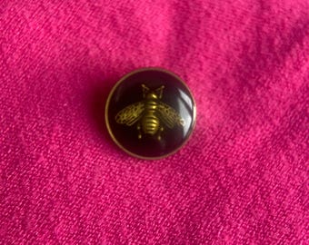 Black enamel button featuring an antique gold-tone bee design.
