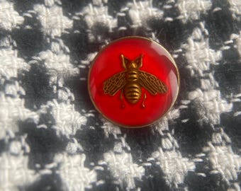 Red enamel button featuring an antique gold-tone bee design.