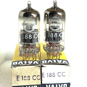 May include: Two vintage vacuum tubes, each in a box with the text "VALVO" and "E 188 CC". The tubes are clear glass with internal components and gold pins. The boxes are yellow and white.