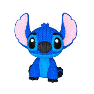 May include: A blue Stitch figurine with large, expressive eyes and ears. The figurine has a knitted texture, with pink inner ears and a black nose. The character is in a sitting position, with small black feet.