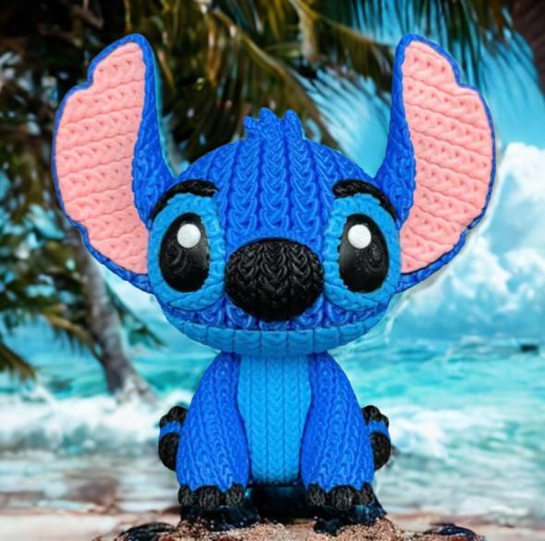 May include: A blue Stitch figurine with large ears and black eyes. The figurine has a knitted texture, with pink inner ears and a black nose. It is posed on a sandy surface with a tropical beach background.