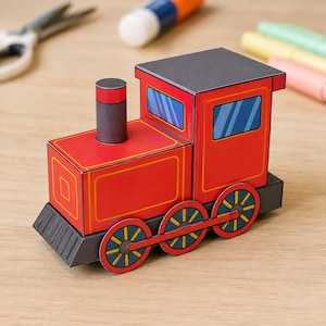 May include: A paper craft model of a red steam locomotive train. The train features a black chimney, a black roof, and three red wheels with blue spokes on each side. The windows are depicted with blue and white diagonal lines on the sides.