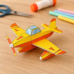 May include: A paper craft aeroplane model featuring a bright yellow and orange colour scheme. The aircraft has a propeller at the front, a cockpit with blue-tinted windows, and two floats attached underneath the wings for a seaplane design.