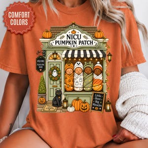 May include: An orange t-shirt featuring a graphic of a storefront labeled NICU PUMPKIN PATCH. The design includes four swaddled infants, a black cat, pumpkins, and a sign reading Little Boos Big Miracles. A red starburst badge reads COMFORT COLORS.