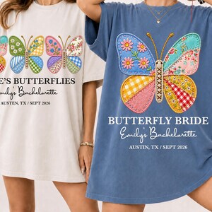 May include: Two t-shirts, one cream and one blue, with butterfly designs. The cream shirt displays multiple butterflies, the blue shirt has one. Text on the shirts reads "E'S BUTTERFLIES" and "BUTTERFLY BRIDE", with "Emily's Bachelorette" and location/date.