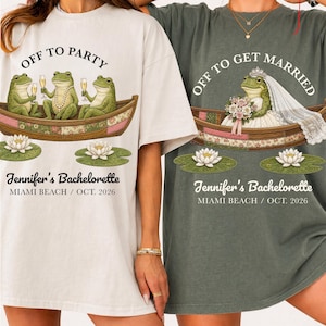 May include: Two oversized t-shirts, one cream and one sage green, featuring frog illustrations in a boat. The cream shirt says "Off to Party" and the green shirt says "Off to Get Married". Both shirts read "Jennifer's Bachelorette, Miami Beach / Oct. 2026".