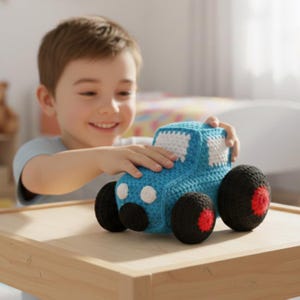 May include: A handmade crochet toy car in shades of blue, white, and black. The car features large black wheels with red accents and white detailing on the roof and headlights. The toy is sitting on a wooden surface.