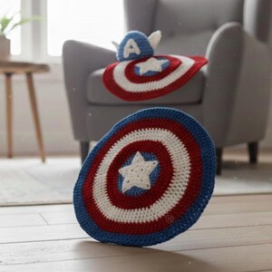 K&ouml;nnte beinhalten: Geh&auml;keltes Baby-Set im Captain America-Design, bestehend aus einem Schild und einem Hut. Das Schild ist blau, rot und wei&szlig;, mit einem Stern in der Mitte. Der Hut ist blau mit wei&szlig;en Fl&uuml;geln und dem Buchstaben "A".