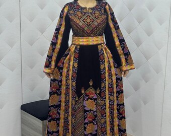 May include: A black dress with long sleeves and intricate embroidery. The dress features a detailed floral and geometric pattern in shades of red, gold, purple, and green. A matching embroidered belt cinches the waist.