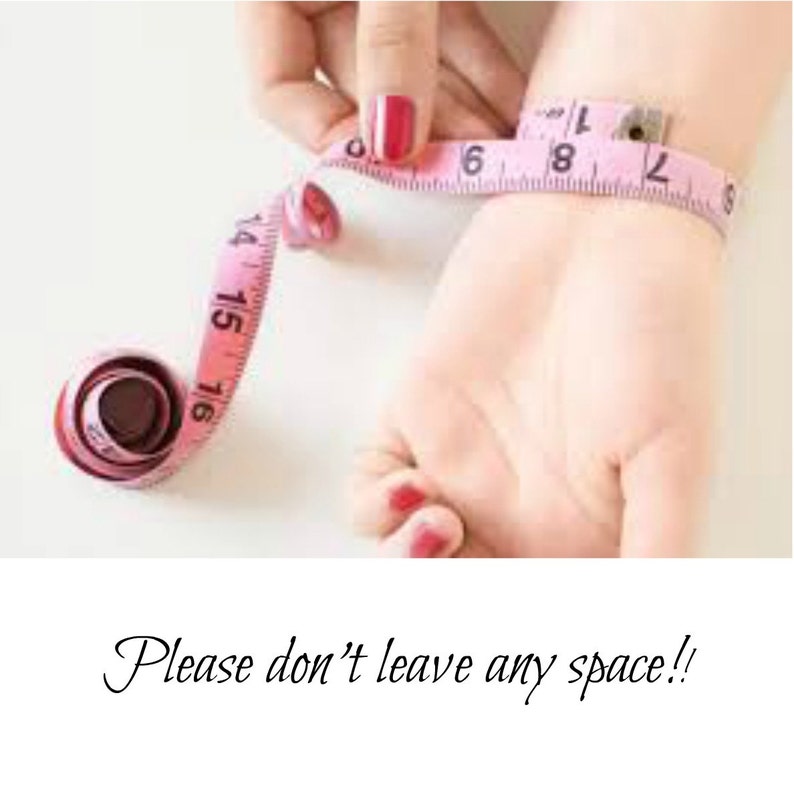May include: A pink measuring tape wrapped around a person's wrist. The tape reads "14, 15, 16, 17, 18, 19, 20, 21, 22".