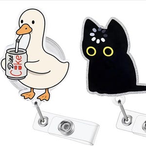 May include: Two badge reels featuring acrylic charms. One charm depicts a white duck with an orange beak drinking from a silver can labeled Diet Coke with a straw. The other charm shows a black cat with yellow eyes and a white loading icon on its head.