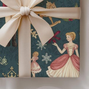 May include: A gift wrapped in dark teal paper featuring a repeating pattern of a ballerina in a pink dress, a rocking horse, a crown, and white snowflakes, finished with a wide, smooth, light beige satin ribbon tied in a large bow on top.