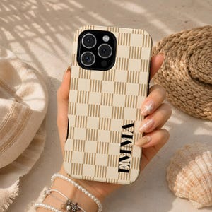 May include: A phone case featuring a beige and cream checkered pattern with vertical stripes within each square. The name EMMA is printed in black capital letters vertically along the right side. The case has a black camera cutout area.