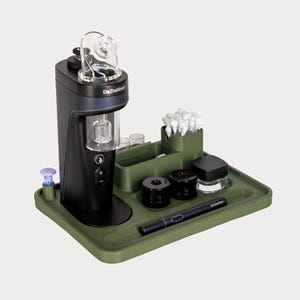 以下が含まれることがあります： 緑色のトレイに「Dr. Dabber」の文字が入った黒と透明の電子機器。トレイにはペン、容器、綿棒も入っています。このデバイスにはガラス部品と紫色のアクセサリーが付いています。