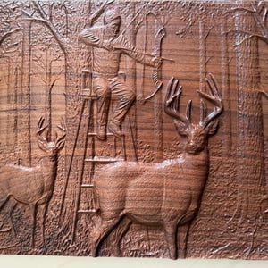 Könnte beinhalten: Ein geschnitztes Holzrelief, das eine Jagdszene darstellt. Ein Jäger zielt mit Pfeil und Bogen von einer Leiter aus, mit zwei Hirschen im Vordergrund. Das Kunstwerk ist in Brauntönen gehalten und zeigt detaillierte Wald- und Tierbilder.