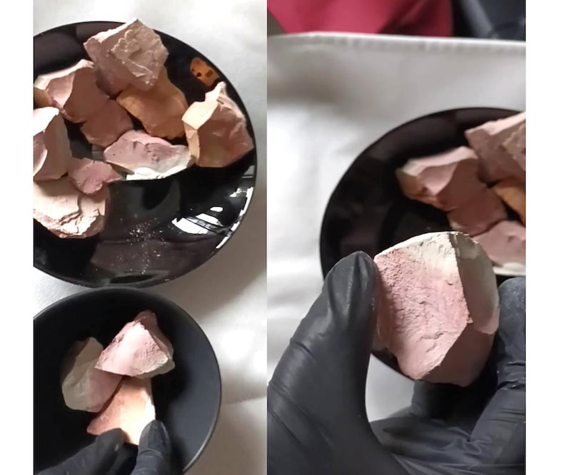 May include: A collection of raw, earthy-toned clay chunks in a black bowl. The clay pieces vary in size and shape, with a mix of pink, beige, and white hues. Some pieces are held by a gloved hand. The image suggests a natural product.
