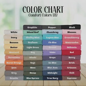 May include: A color chart for Comfort Colors 1717 t-shirts, displaying a large stack of folded fabric swatches in various shades. Each swatch is labeled with its specific color name, including white, black, blue, green, red, and yellow tones.