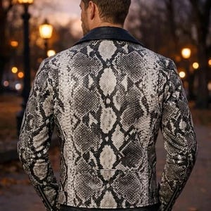 May include: A black and white snakeskin-patterned leather jacket with a black collar and zipper details. The jacket is worn by a person in an outdoor setting with blurred background lights.