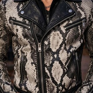 May include: A black and white snakeskin-patterned leather jacket with a black leather collar and lapels. The jacket has multiple silver zippers and a classic biker jacket design.