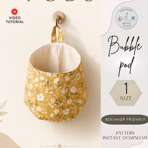 May include: A yellow floral fabric bubble pod hanging on a wall. The pod has a cream-colored interior and a loop for hanging. The text "Bubble pod" and "1 SIZE" are visible.