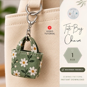 Op de afbeelding: Een miniatuur tasbedel van groene stof met een wit madeliefjespatroon, bevestigd aan een zilverkleurige metalen draaisluiting. De bedel hangt aan een grotere crèmekleurige canvas tas. Tekst: Tote Bag Charm, 1 Size, Beginner Friendly, Sewing Pattern Instant Download, Video Tutorial.