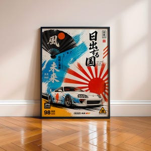May include: A framed vertical poster featuring a white sports car with blue graphic accents. The background displays a black folding fan, a red sun, and Japanese calligraphy. Text includes "The Land of the Rising Sun," "JPN," and "98."