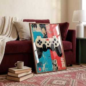 Op de afbeelding: Een ingelijste verticale wandkunstprint met een gestileerde videogamecontroller gecentreerd op een gespleten blauwe en rode achtergrond. Het ontwerp bevat verweerde texturen, zwarte inktillustraties en Japanse karakters in wit en zwart.