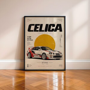 May include: A framed poster featuring a white Toyota Celica GT-Four ST205 with red and black racing decals. The design includes a large yellow circle, the text CELICA, ST205, 1994-1999, and Japanese characters on a cream-colored background.